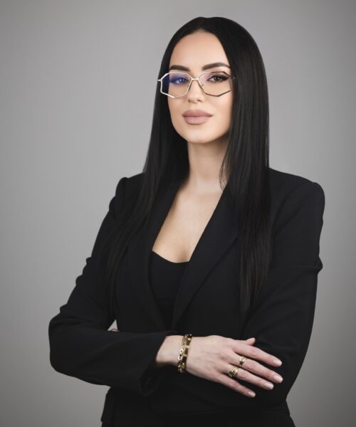 Andrea in formal attire seated elegantly.