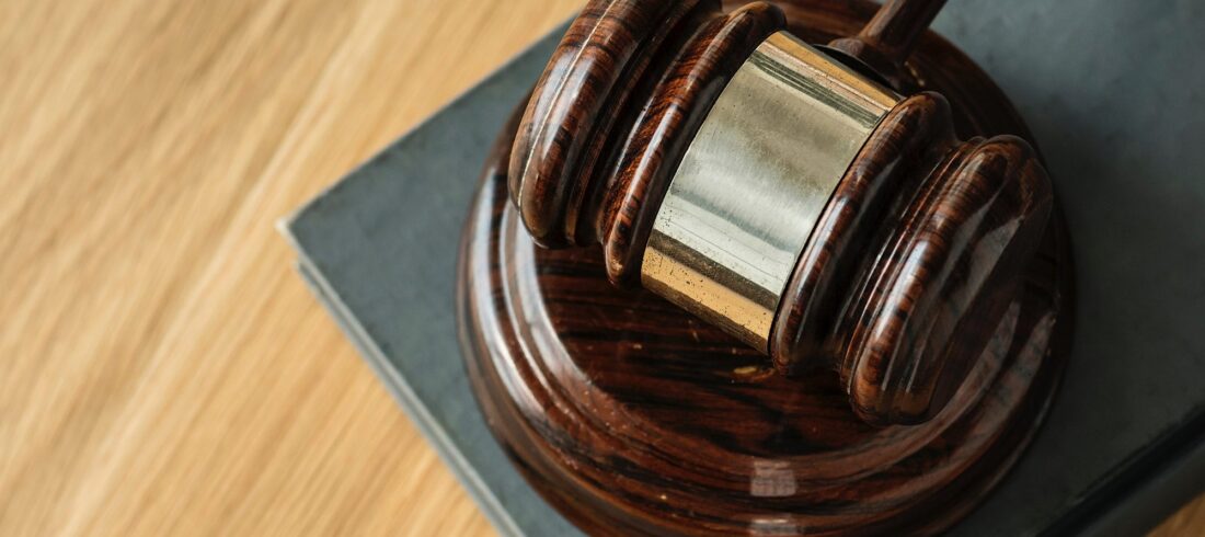 Wooden gavel resting on an open law book, representing litigation, judicial proceedings, and expert legal counsel.