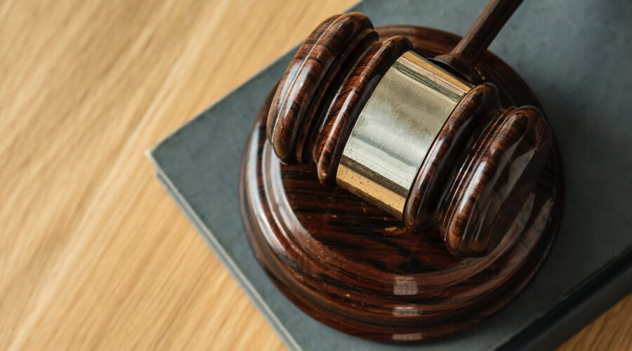 Wooden gavel resting on an open law book, representing litigation, judicial proceedings, and expert legal counsel.