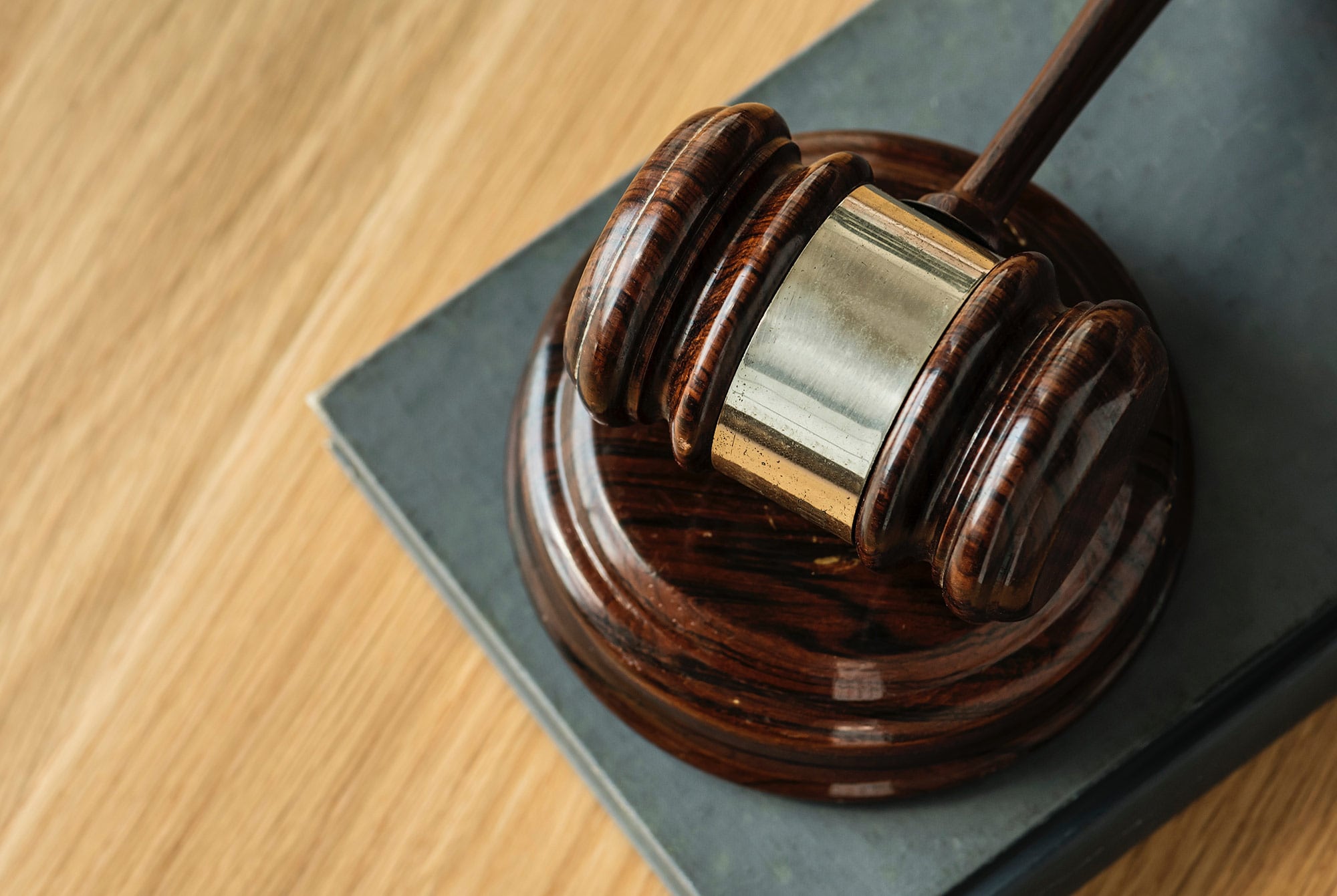 Wooden gavel resting on an open law book, representing litigation, judicial proceedings, and expert legal counsel.